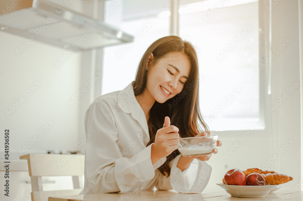 Young woman asia wake up refreshed in the morning and relaxing eat coffee, cornflakes, bread and apple for breakfast at house on holiday. Asian, asia, relax, breakfast, refresh, lifestyle concept.
