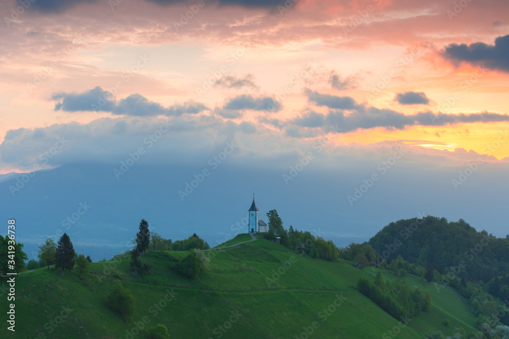 Charming little St. Primus and Felician church in Jamnik, Julian Alps, Slovenia and beautiful sunrise sky colors