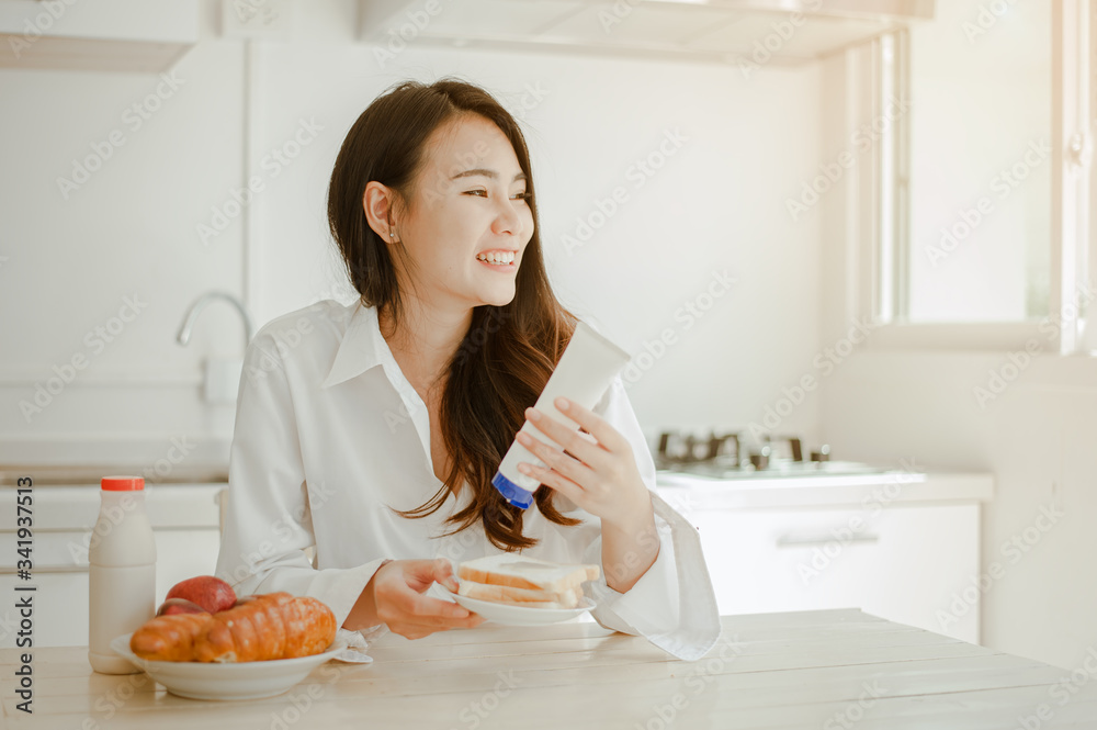 Young woman asia wake up refreshed in the morning and relaxing eat coffee, cornflakes, bread and apple for breakfast at house on holiday. Asian, asia, relax, breakfast, refresh, lifestyle concept.