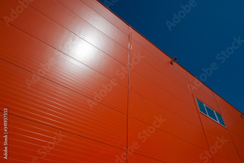 orange wall with a window and a video camera for observation against a blue sky.