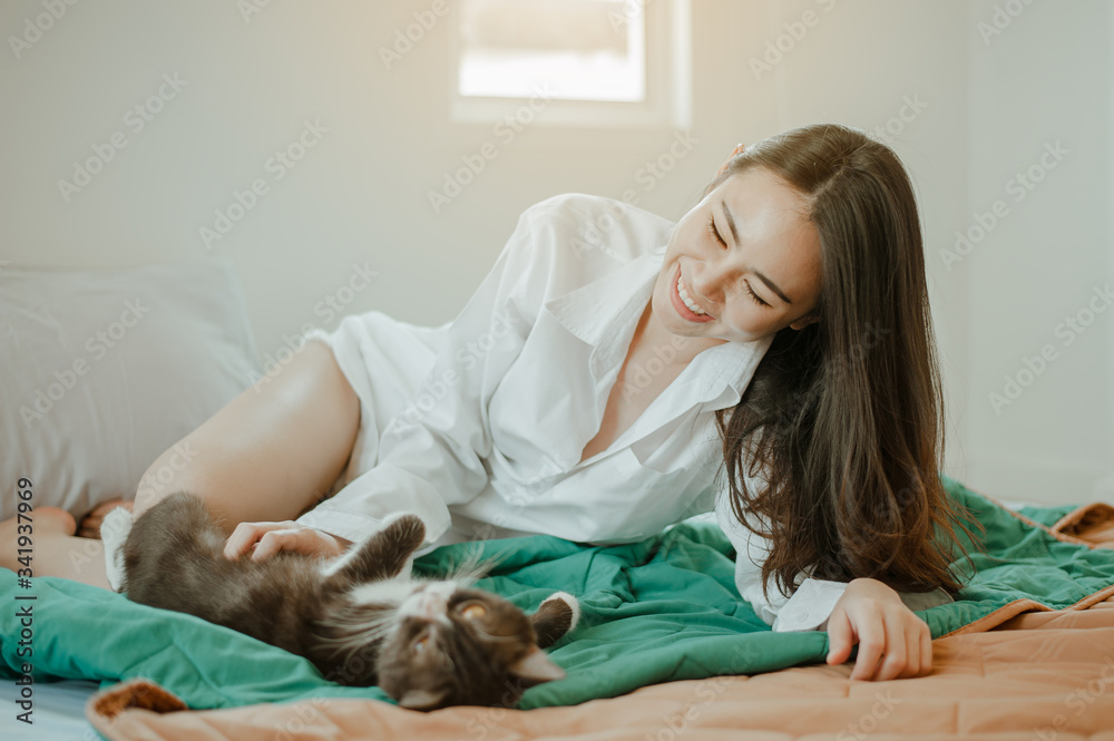 Young woman asia wake up refreshed in the morning playing with cats at bed happily on holiday. Asian, asia, relax, happiness, refresh, lifestyle concept. Young woman asia wake up refreshed in the morning playing with cats at bed happily on holiday. Asian, asia, relax, happiness, refresh, lifestyle concept.