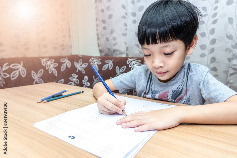 Little boy writing homework on wooden table at home. Kid learing and writing alphabet looking very happy. Little boy writing homework on wooden table at home. Kid learing and writing alphabet looking very happy.