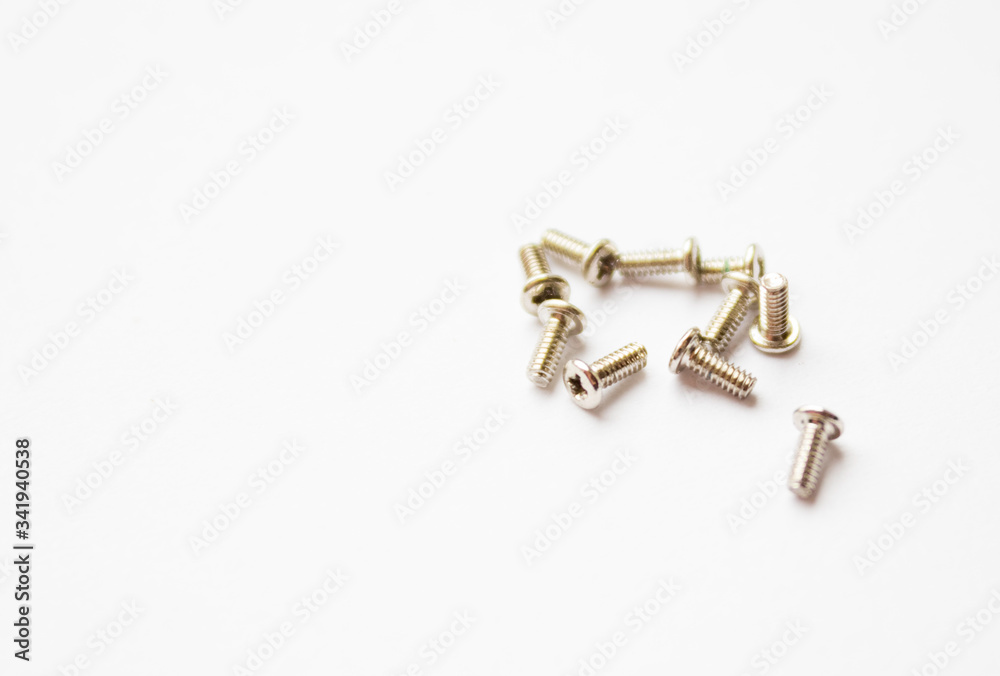 Small screws on a white background. Free space for text. Small screws on a white background. Free space for text.