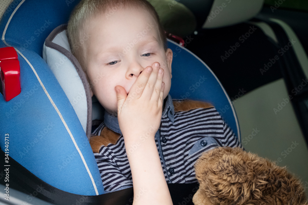 The child was rocked in a car seat. The boy suffers from kinetosis and motion sickness. The concept of motion sickness and vomiting in the car - obrazy, fototapety, plakaty 