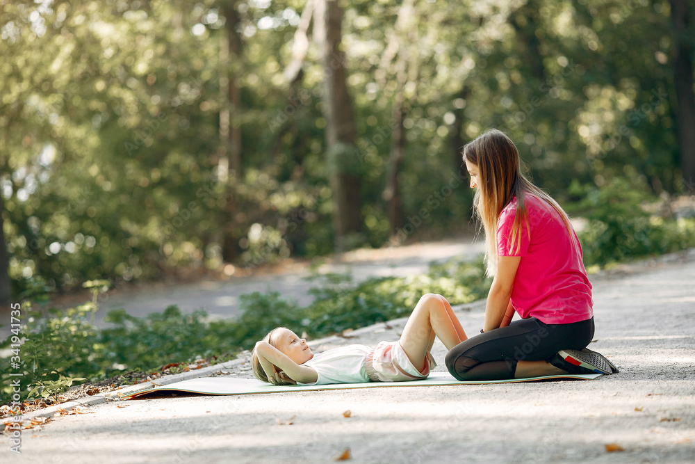 Beautiful mother with little daughter. Girls doing yoga. Family in a sportswear.