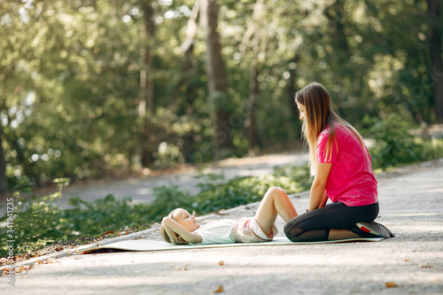 Beautiful mother with little daughter. Girls doing yoga. Family in a sportswear.