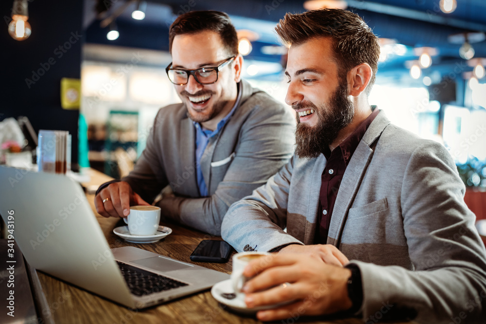 Group of attractive young business men colleagues working together in cafe