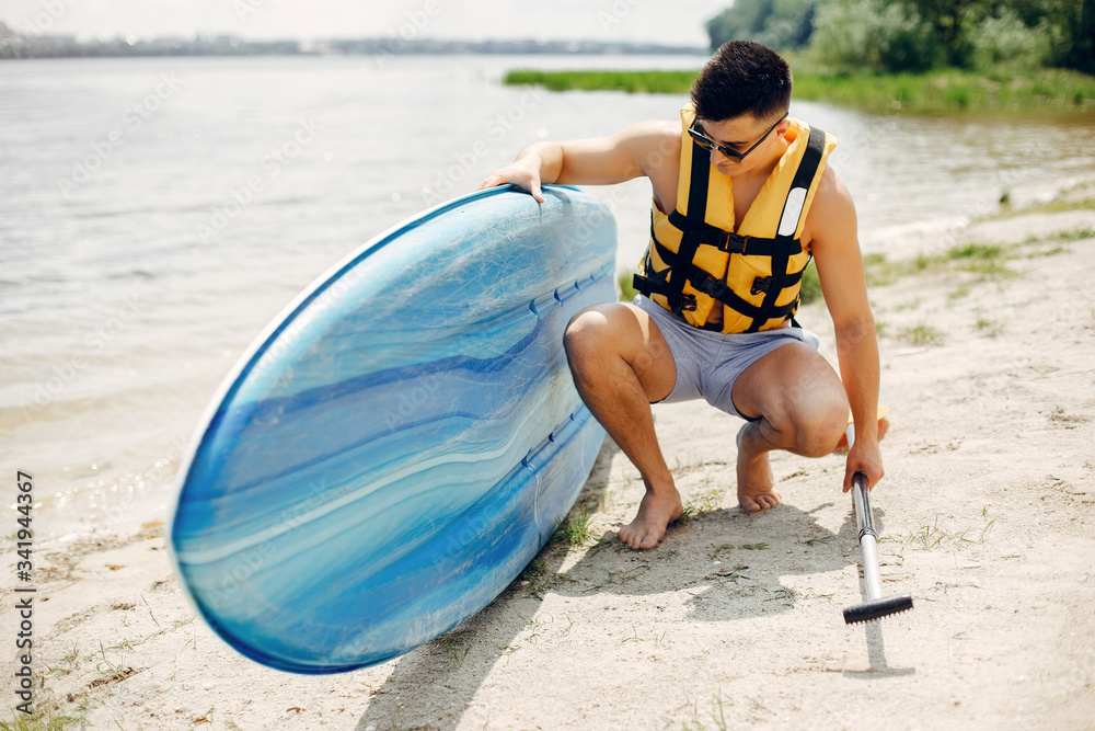 Obraz premium Handsome man with a sup. Surfer in a yellow vest.
