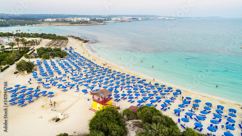 Aerial bird's eye view of famous Makronissos beach coastline, Ayia Napa, Famagusta, Cyprus. Landmark sea tourist attraction Makronisos bay at sunset with golden sand, sunbeds in Agia Napa from above. photo