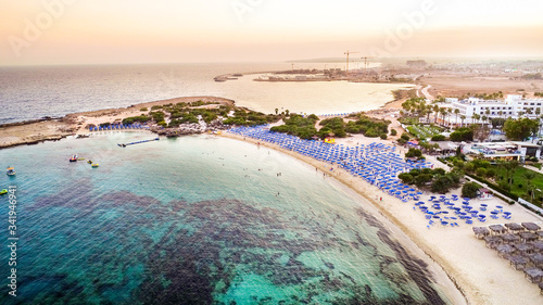 Aerial bird's eye view of famous Makronissos beach coastline, Ayia Napa, Famagusta, Cyprus. Landmark sea tourist attraction Makronisos bay at sunset with golden sand, sunbeds in Agia Napa from above. photo