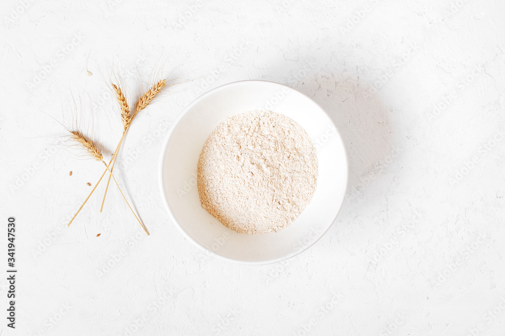 Wholegrain flour in the bowl on the white textured table Wholegrain flour in the bowl on the white textured table