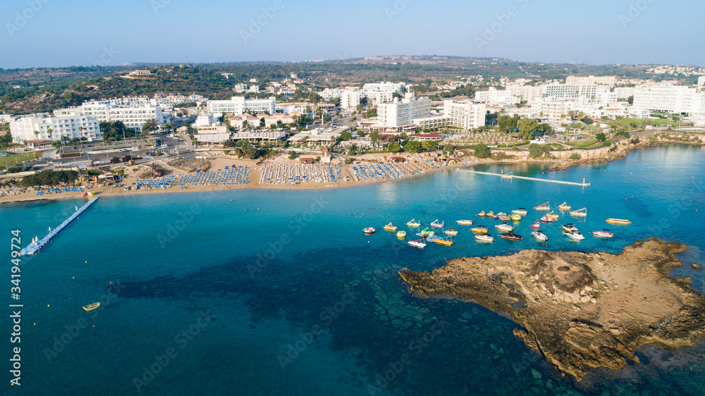 Aerial bird's eye view of Fig tree bay in Protaras, Paralimni, Famagusta, Cyprus. Tourist attraction golden sandy beach with boats, sunbeds, sea restaurants, water sports on summer holidays from above