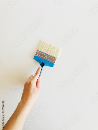paint brush in a female hand against a white wall