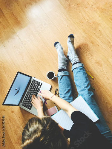 girl sitting on the floor with a laptop. Nearby lies a notebook, mug with coffee and a telephone photo