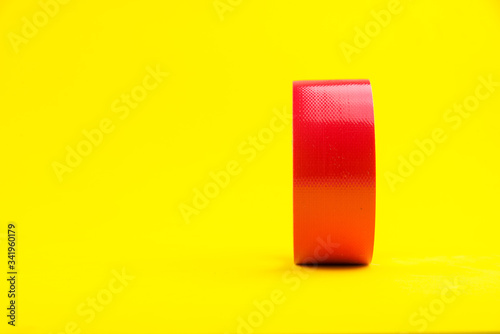 A roll of red duct tape isolated on a yellow background.