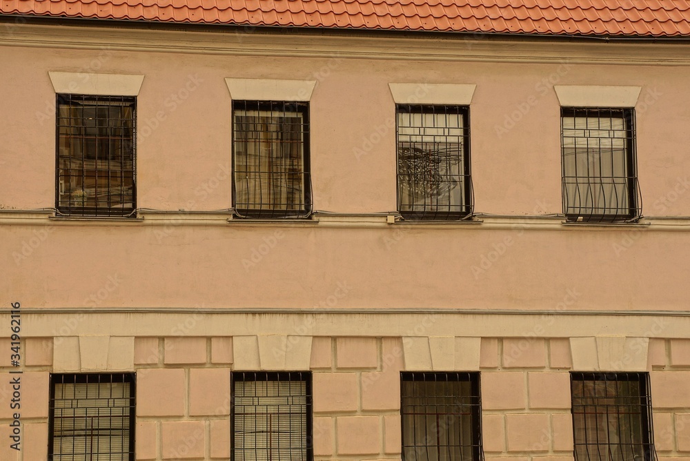texture of a row of old windows with iron bars on the brown concrete wall of the building