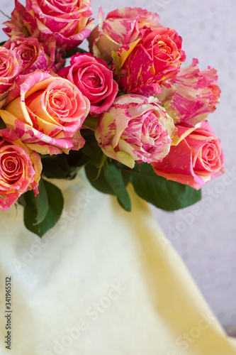 A bouquet of pink flowers. White fabric, beige fabric, plain fabric. Two-tone roses, pink and yellow roses