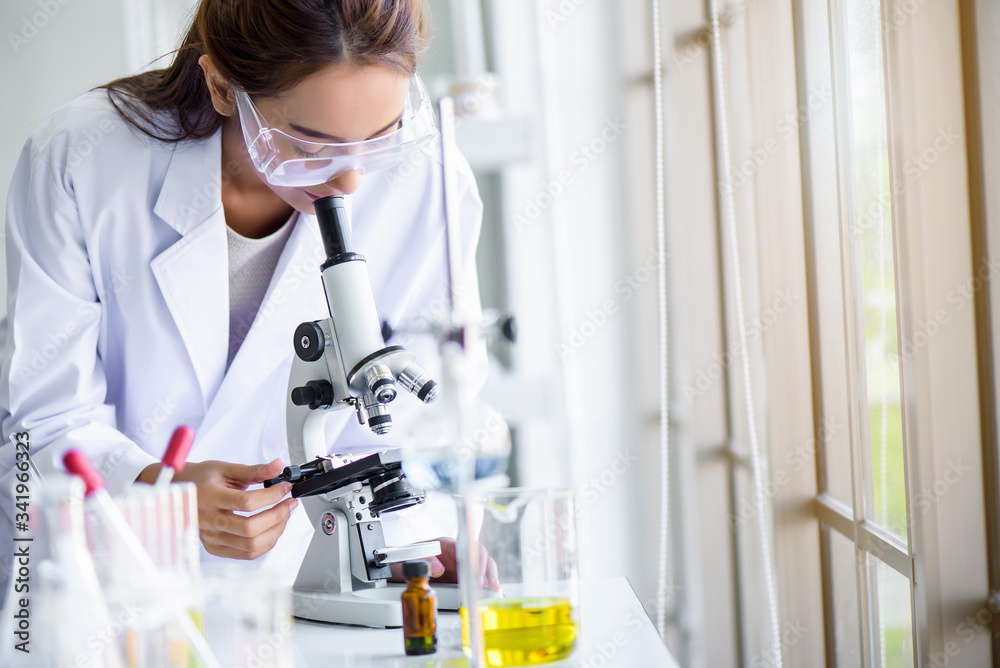 Attractive young Asian scientist woman lab technician assistant analyzing sample in test tube at laboratory. Medical, pharmaceutical and scientific research and development concept. Attractive young Asian scientist woman lab technician assistant analyzing sample in test tube at laboratory. Medical, pharmaceutical and scientific research and development concept.
