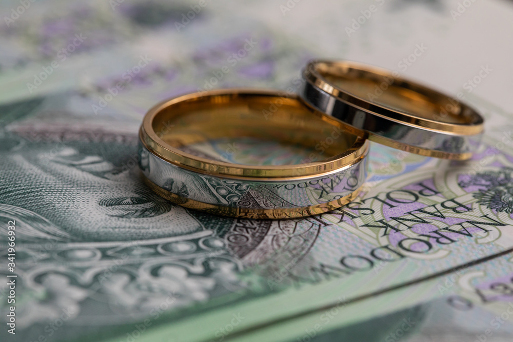Gold wedding rings surrounded by a stack of Polish banknotes. Gold wedding rings surrounded by a stack of Polish banknotes.