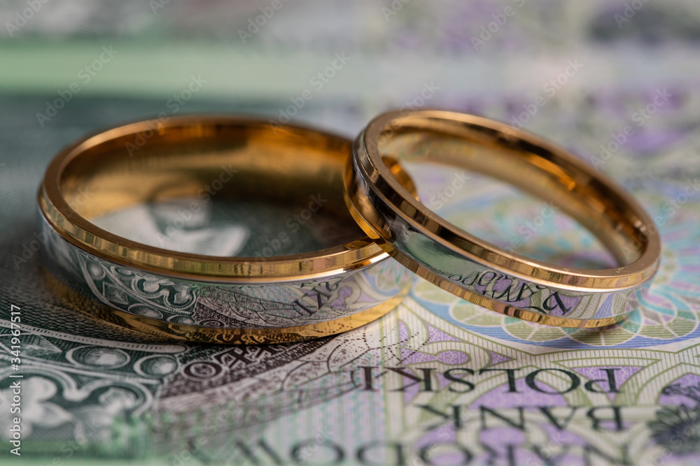 Gold wedding rings surrounded by a stack of Polish banknotes. Gold wedding rings surrounded by a stack of Polish banknotes.
