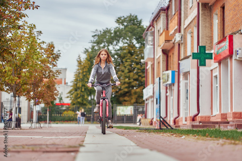 The girl rides a bicycle on the sidewalk near the pharmacy. © Aleksandr