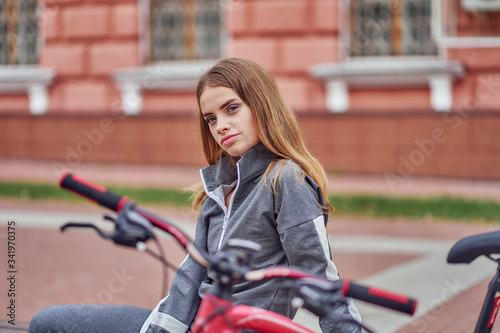 A woman is resting from cycling on a city bench.