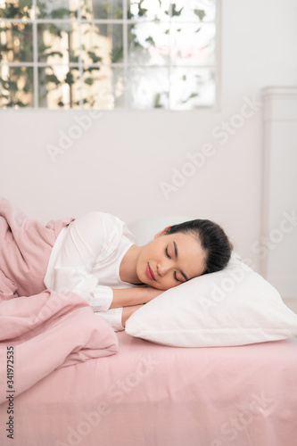Young beautiful woman sleeping in her bed and relaxing in the morning
