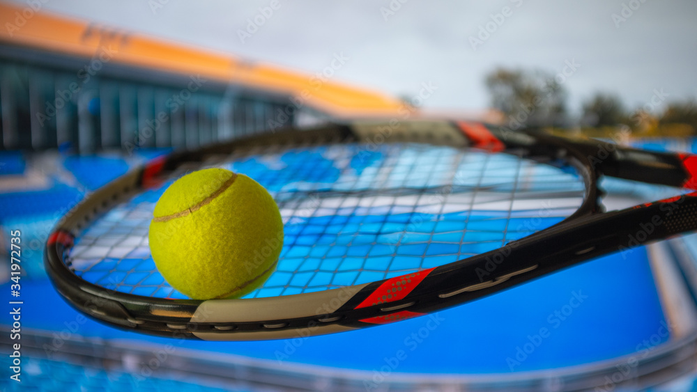 Tennis racket and a ball, with a blue hard court background 