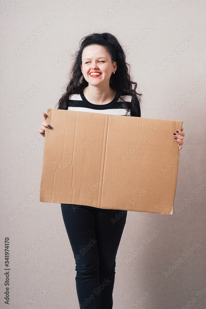 A woman holds a blank kraft paperboard. Gray background A woman holds a blank kraft paperboard. Gray background