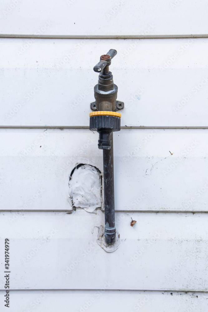 Old dirty brass external garden water tap on an exterior wall. Old dirty brass external garden water tap on an exterior wall.