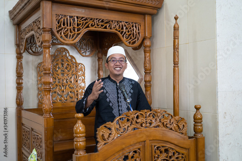 portrait of muslim male preacher sharing about islam during prayer time in the mosque photo