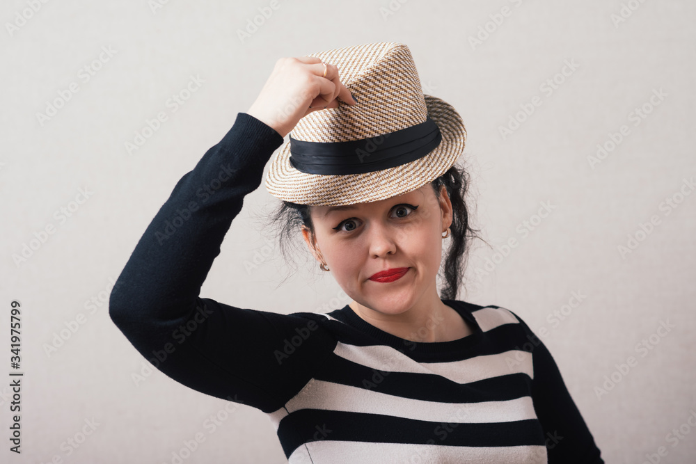 Woman takes off his hat and clothes. Gray background. Woman takes off his hat and clothes. Gray background.
