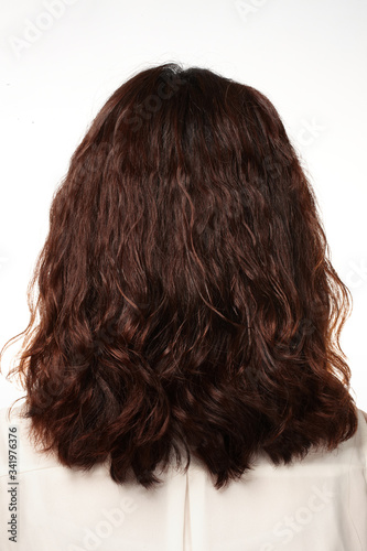 the back of a woman with a half-curly long brown hair.