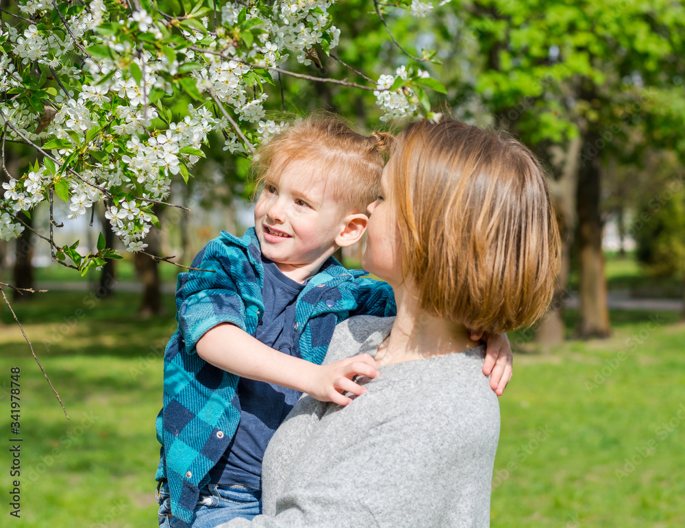 Mom with her little boy near a flowering tree in the park Mom with her little boy near a flowering tree in the park