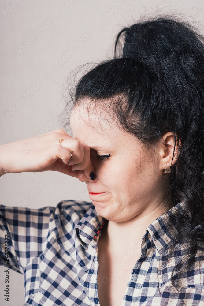 woman covering her eyes, hand covering her nose. On a gray background. woman covering her eyes, hand covering her nose. On a gray background.
