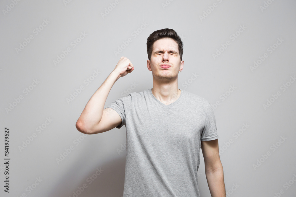 A guy in a gray T-shirt with emotions on his face. A guy in a gray T-shirt with emotions on his face.
