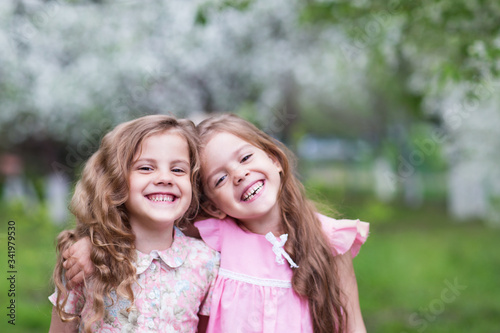 Two girls laughing in a blooming garden
