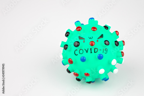 Green rubber ball with colorful thorns writing a virus Covid-19 on a white background