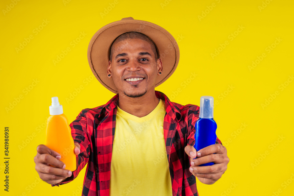 afro brazilian man choosing spf bottle in studio yellow wall afro brazilian man choosing spf bottle in studio yellow wall