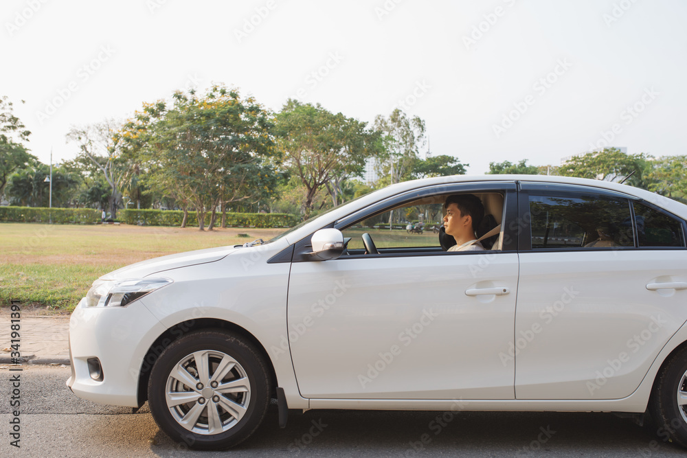 Riding his new car. Side view of handsome young man driving his car and smiling