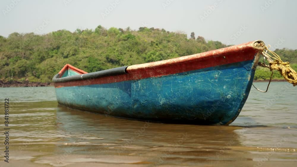 A wooden fishing boat floats on the surface of the river near the shore A wooden fishing boat floats on the surface of the river near the shore