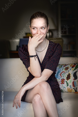 Canvas-taulu Portrait of petite teenage girl giggling with her hand over her mouth looking aside