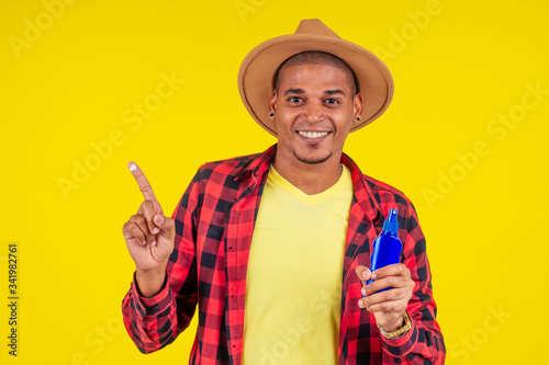 afro brazilian man choosing spf bottle in studio yellow wall
