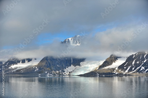 A glacier creeps from the mountains into the sea water.