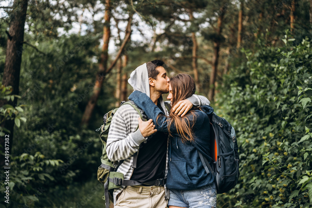 Young couple with backpacks on their backs smiling and walking in the forest, enjoy the walk Young couple with backpacks on their backs smiling and walking in the forest, enjoy the walk