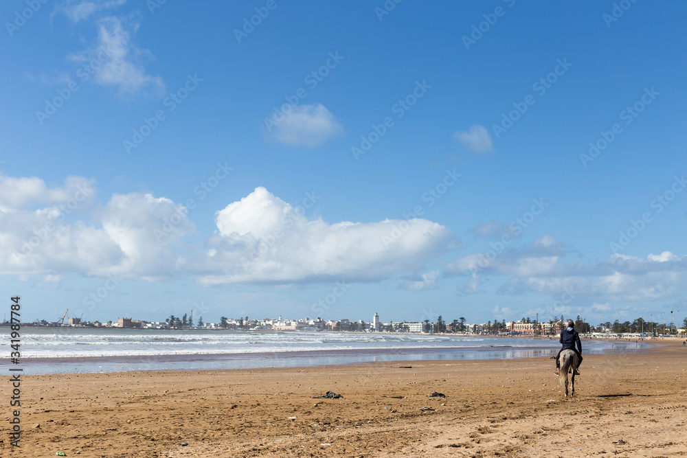 quiet beach with a rider riding a horse