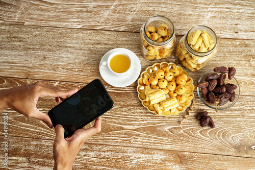 gesture of hand using mobile phone taking picture of indonesian traditional snack photo