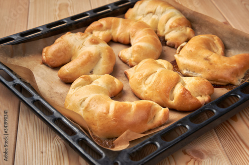 Fresh bakery. Oven-baked croissants with sugar icing on a baking sheet covered with parchment paper.