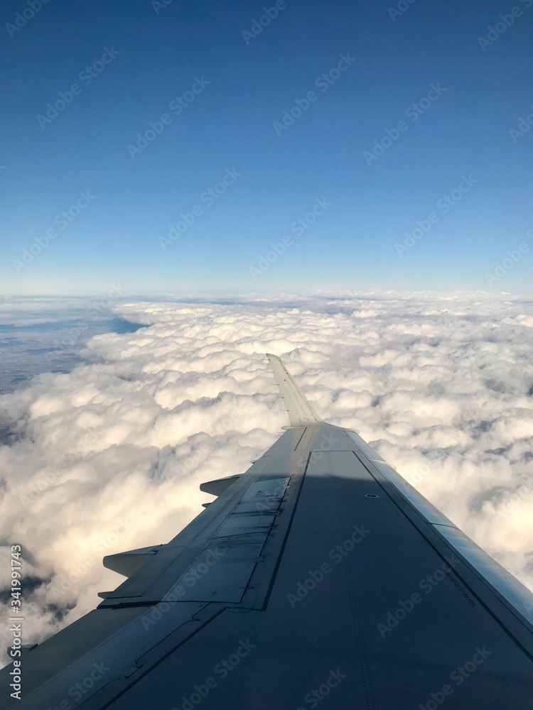 High up in the stratosphere, close to heaven: Above the white clouds on a scenic journey in an airplane flight of a vacation journey seeing the aircraft wing gliding over the bright cloudscape High up in the stratosphere, close to heaven: Above the white clouds on a scenic journey in an airplane flight of a vacation journey seeing the aircraft wing gliding over the bright cloudscape