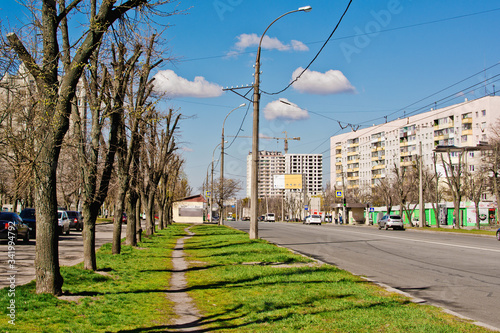 traffic on a city street on a sunny day against a blue cloudy sky and houses
